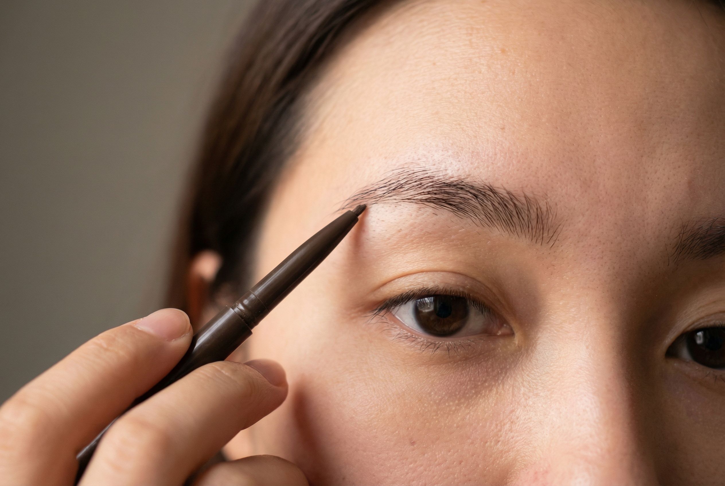 Close-up of brow pencil filling technique showing short hair-like strokes